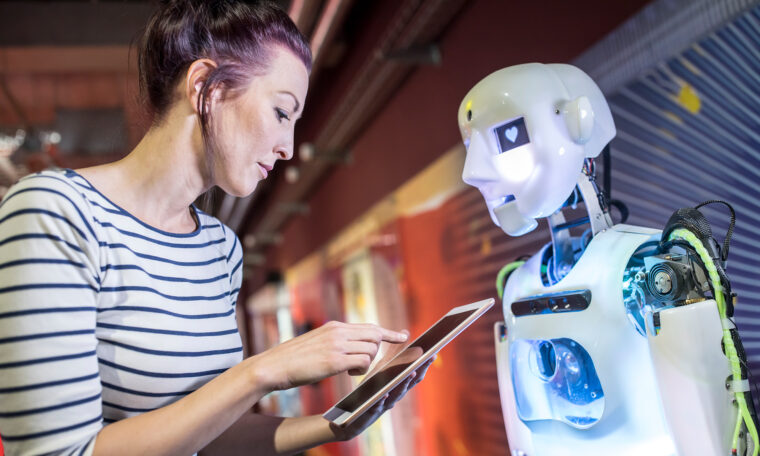 kvinna knappar på Ipad mittemot människoliknande robot