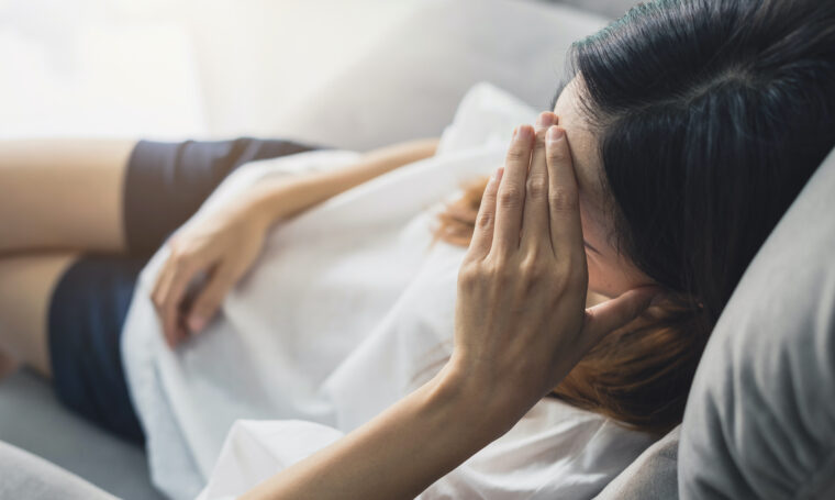 kvinna ligger på soffa med huvudvärk