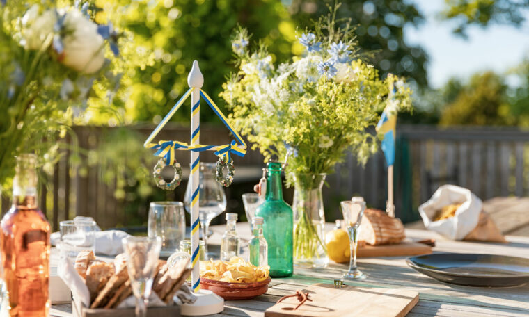 uppdukat bord sommar utomhus med midsommarkrans och blommor