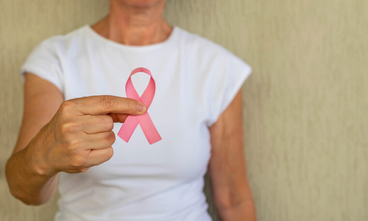 Kvinna håller fram rosa bandet, bröstcancersymbol