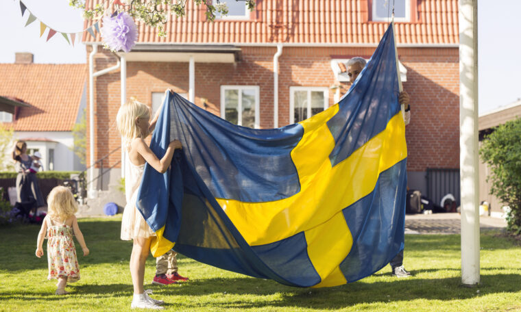 Pappa med döttrar och svensk flagga.