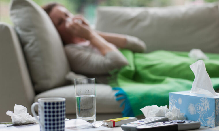 förkyld kvinna nerbäddad i soffan