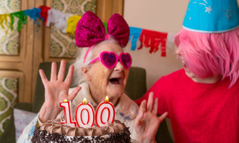 Kvinna med partyhatt och partyglasögon firar 100 år