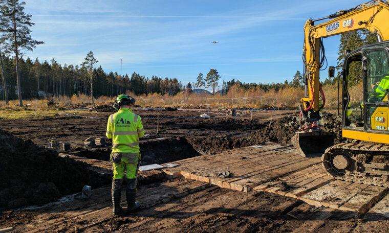 Utgrävningen i Logsjömosse. Arkeolog vid utgrävning och arbetsfordon.