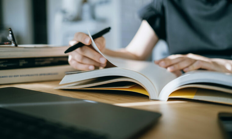 uppslagen bok på skrivbord, kvinna i bakgrunden