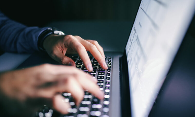 man bokför på datorn i mörkt rum