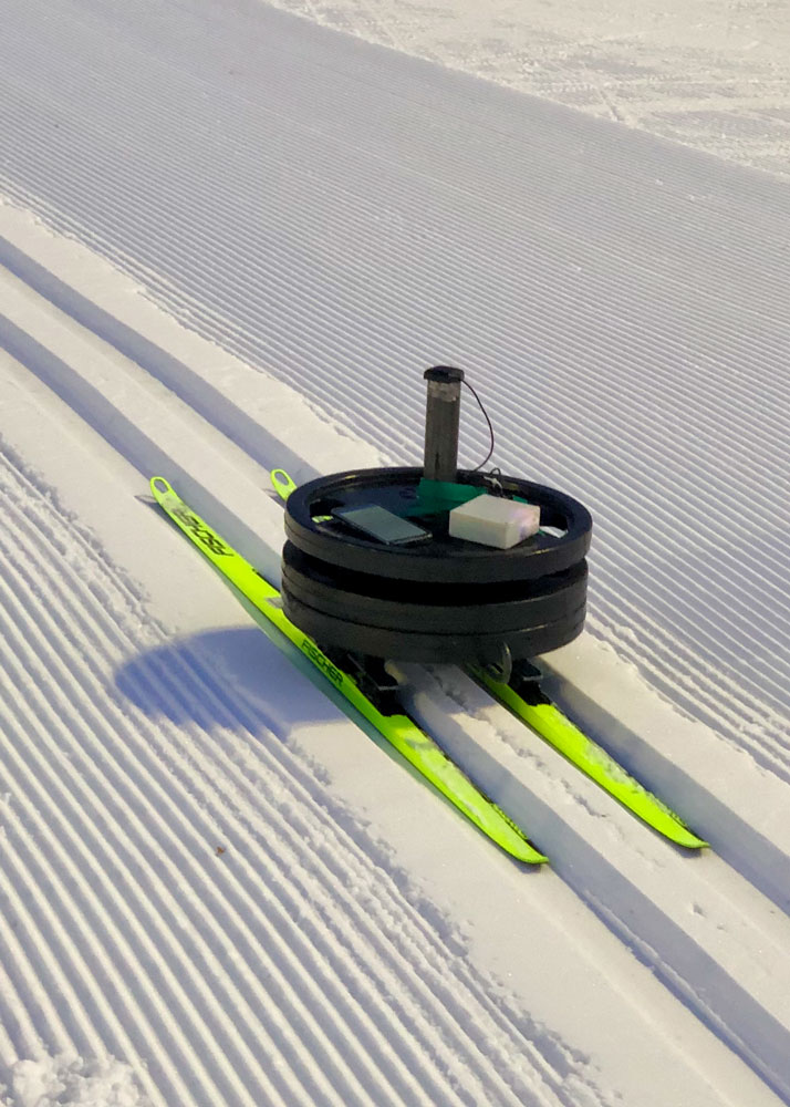 rund liten robot glider på gula skidor i skidspår