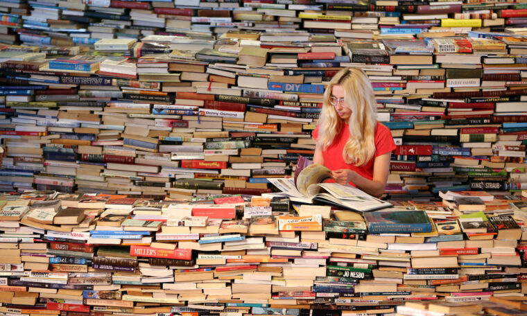 kvinna sitter i ett hav av böcker
