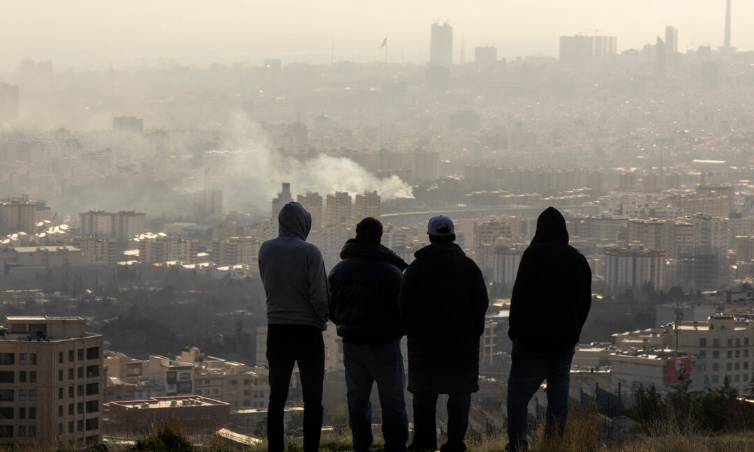 rök från en bomb i Teheran, fyra män tittar på