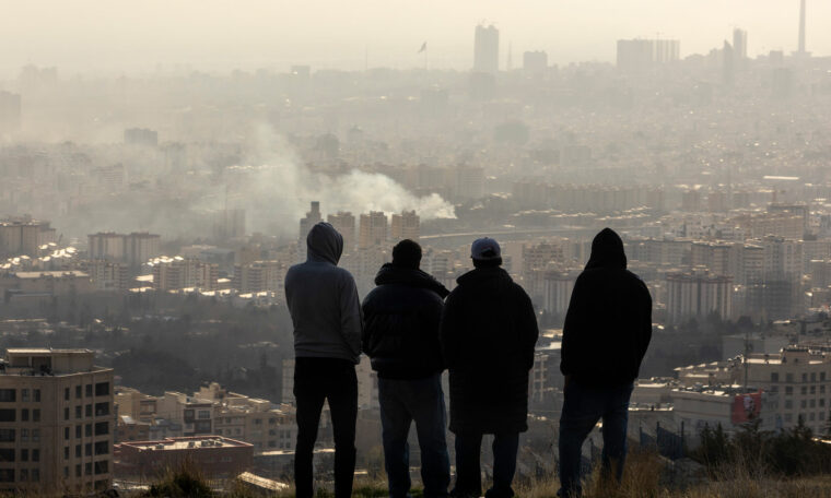 rök från en bomb i Teheran, fyra män tittar på