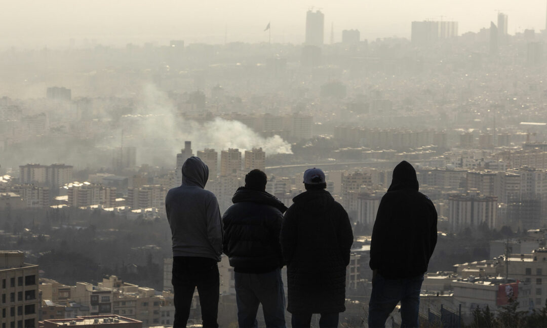 rök från en bomb i Teheran, fyra män tittar på