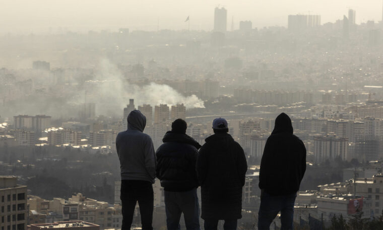 rök från en bomb i Teheran, fyra män tittar på
