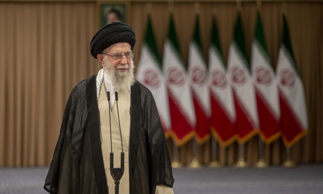 Ayatolla Ali Khamenei talar framför flera iranska flaggor.