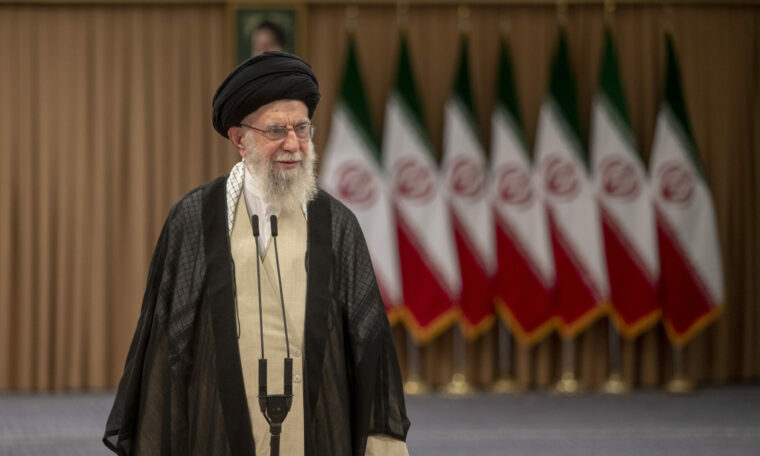 Ayatolla Ali Khamenei talar framför flera iranska flaggor.