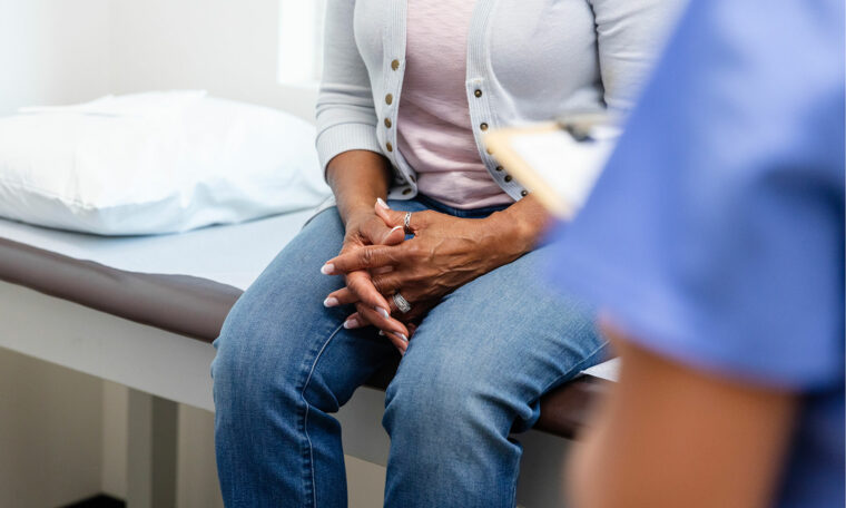 kvinna sitter på brits hos läkare