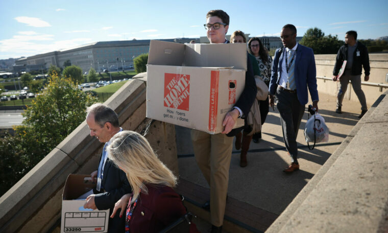 Journalister går nerför en trappa med flyttkartonger.