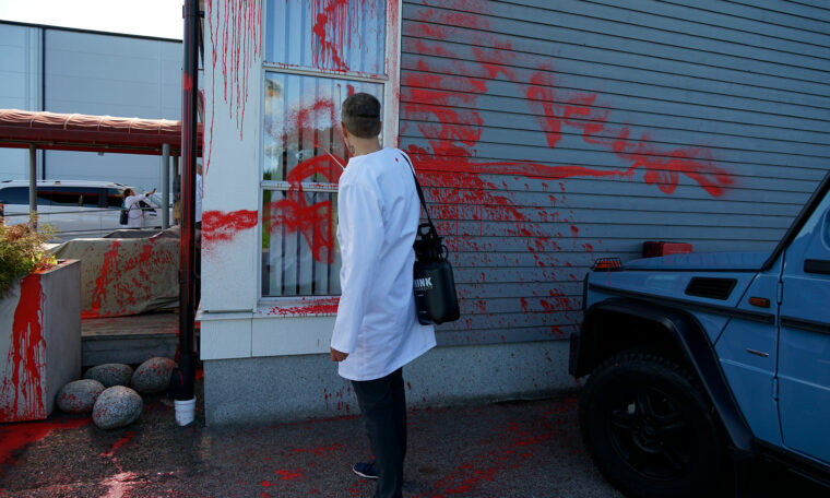 Forskaraktivist sprejar röd färg på vit vägg