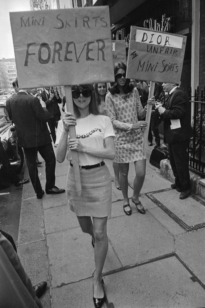 unga kvinnor med skyltar ”Mini skirts forever”