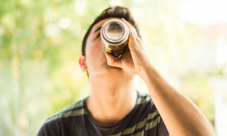 ung pojke srucker energidryck ur burk