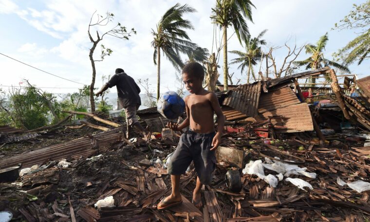 Pojken Samuel går igenom ruinerna av sitt familjehem tillsammans med sin far Phillip, den 16 mars 2015 i Port Vila, Vanuatu.