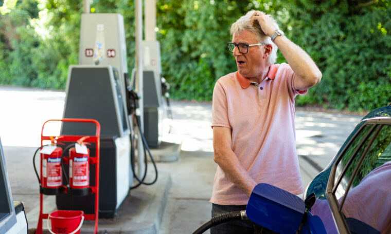 Äldre man som tankar bilen tittar chockat mot prisdisplayen.