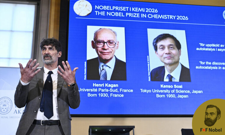 Heiner Linke håller upp sina händer framför en skärm med porträtt av Nobelpristagarna i kemi Henri Kagan och Kenso Soai.